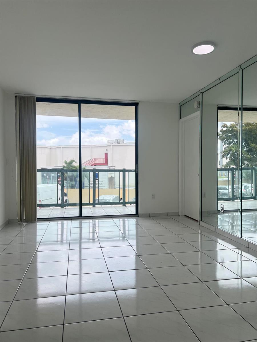 A bright room with white tile floors, a sliding glass door to a balcony, and mirrored walls — 2055 SW 122nd # 219, Miami FL 33175, MIAMI, FL