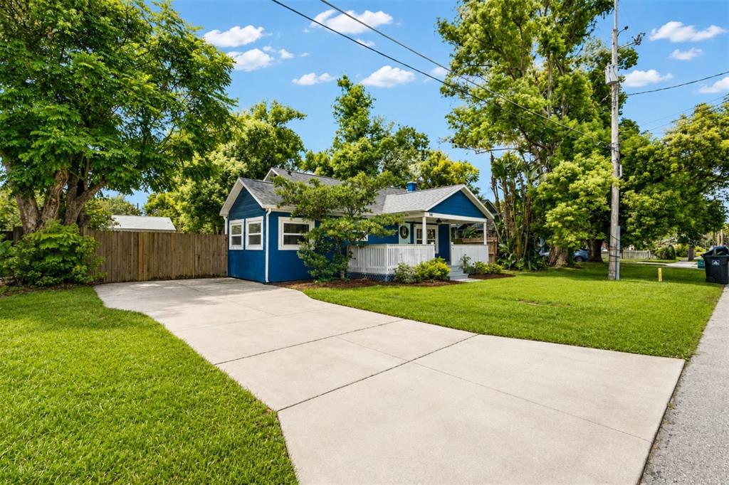 A blue house with a white porch and a concrete driveway sits on a grassy lot — 140 PAGE STREET, ORLANDO, FL