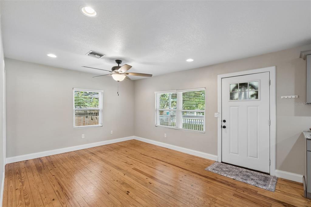 A room with light-colored walls, hardwood floors, a ceiling fan, and a white front door — 140 PAGE STREET, ORLANDO, FL