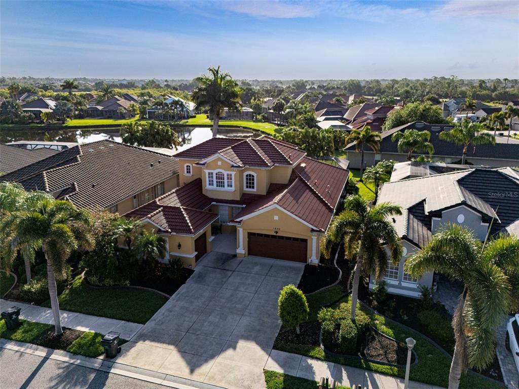 An aerial view of a two-story suburban house with a tile roof and concrete driveway — 1230 CREEK NINE DRIVE, NORTH PORT, FL