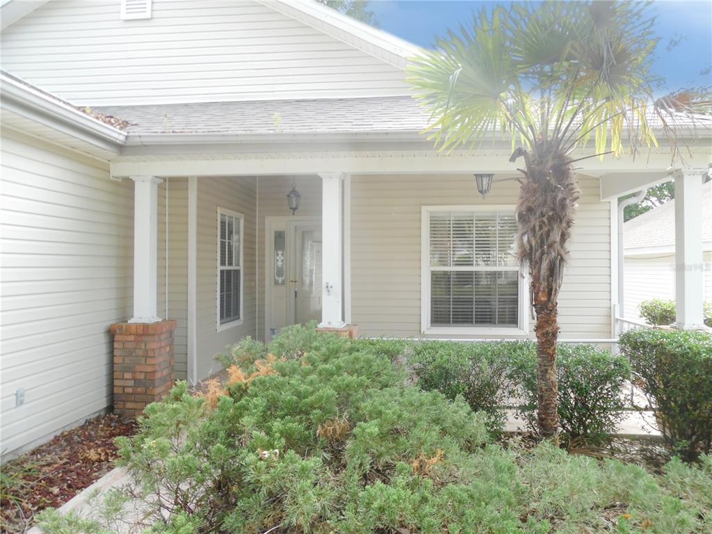 A covered front porch with a brick-based column, a palm tree, and landscaping — 24947 CRANES ROOST CIRCLE, LEESBURG, FL