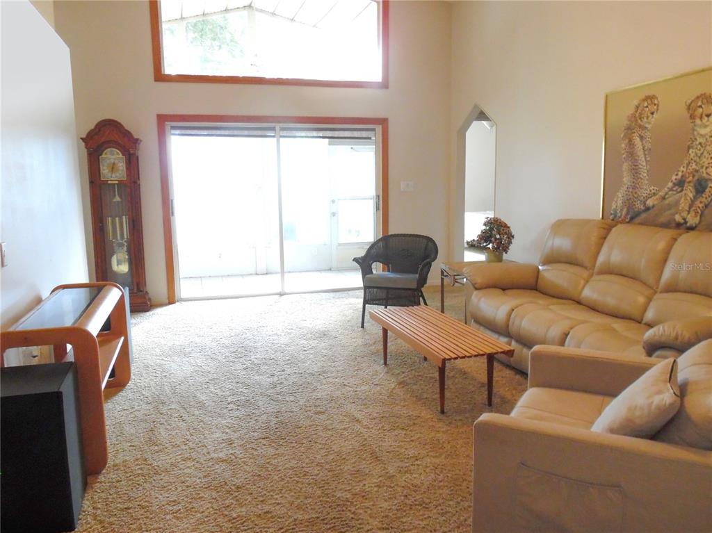 An empty living room features beige wall-to-wall carpeting, white walls, and a decorative column — 24947 CRANES ROOST CIRCLE, LEESBURG, FL
