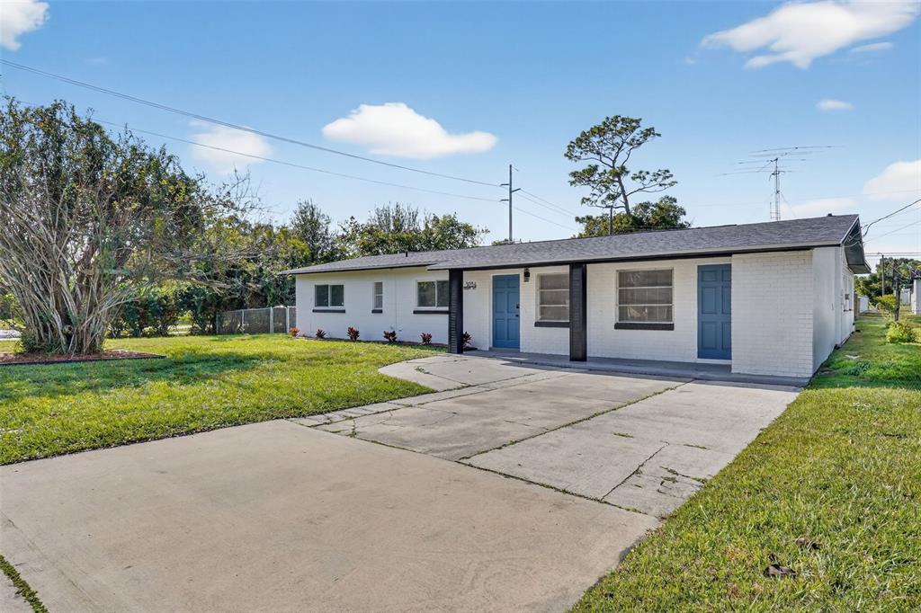 A single-story white brick house with a concrete driveway and two blue front doors — 3034 TOURAINE AVENUE, ORLANDO, FL