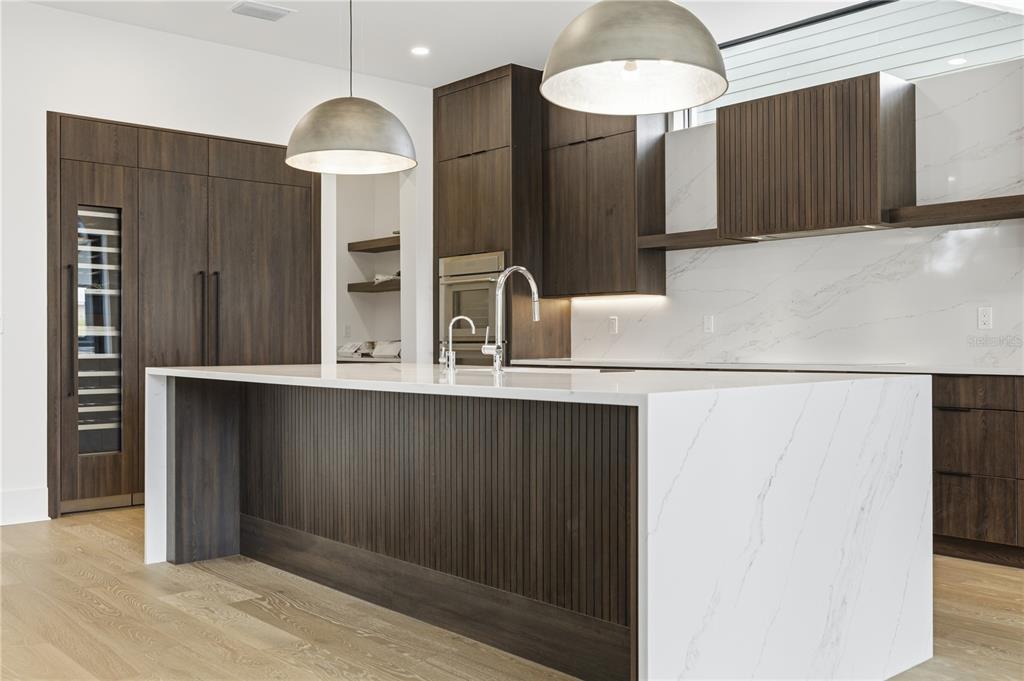 A modern kitchen features a large waterfall island, dark wood cabinetry, and white marble countertops — 904 W FRIBLEY STREET, TAMPA, FL