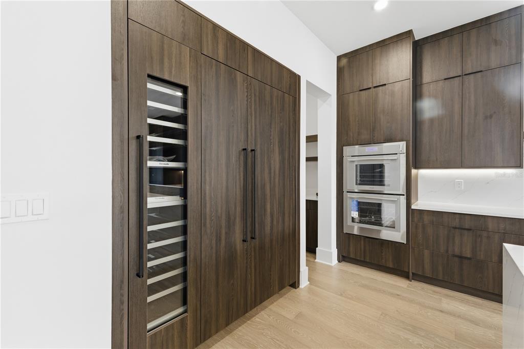 A modern kitchen features dark wood cabinetry, integrated appliances, and light hardwood flooring — 904 W FRIBLEY STREET, TAMPA, FL