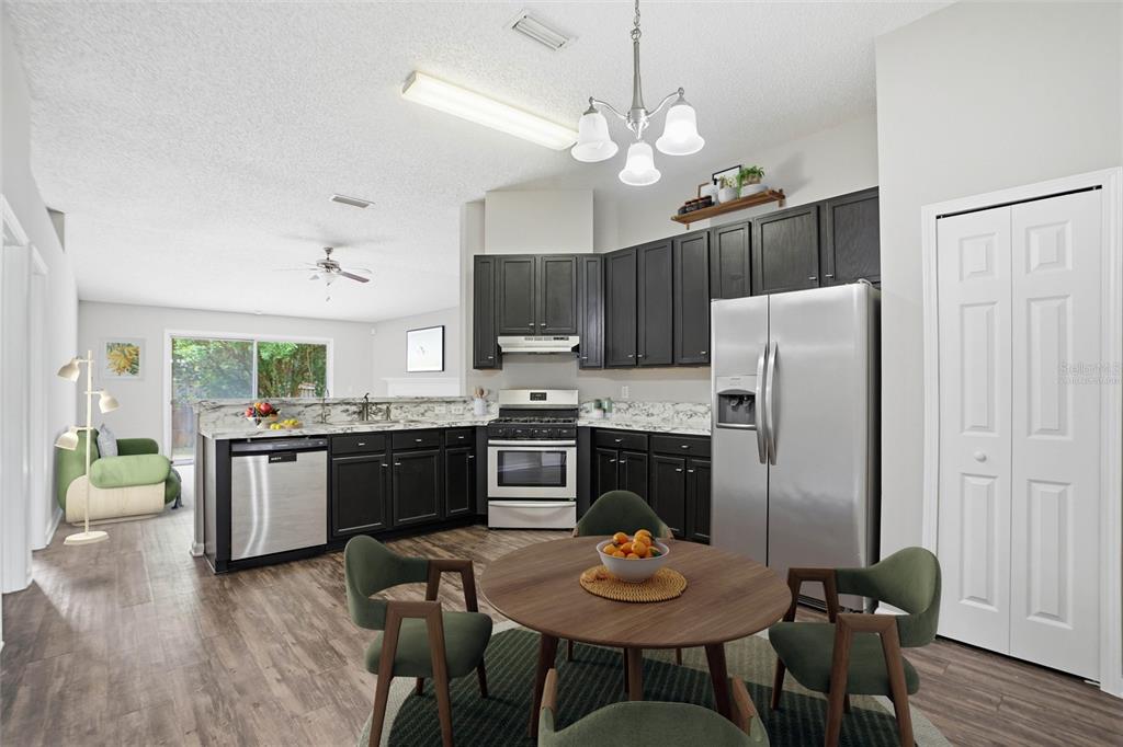 A kitchen with dark cabinets, stainless steel appliances, and a round dining table with chairs — 5736 GUANA PARK COURT, JACKSONVILLE, FL