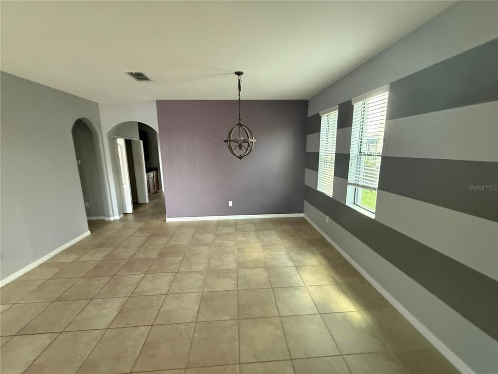 A dining room features a dark accent wall, striped gray walls, and tile flooring — 1890 ALTAVISTA CIRCLE, LAKELAND, FL
