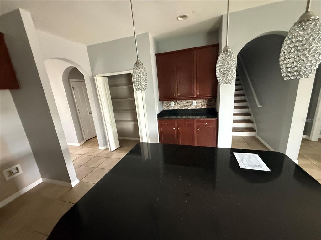 A kitchen island with a black countertop sits before dark wood cabinets and a pantry — 1890 ALTAVISTA CIRCLE, LAKELAND, FL