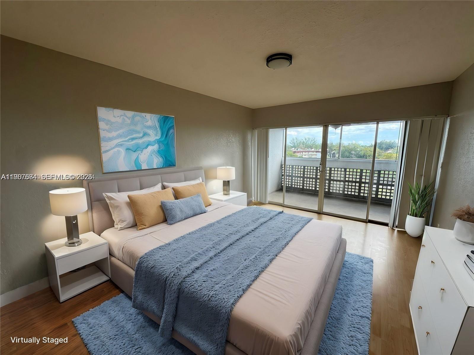 A bedroom features a bed with blue bedding, two nightstands, and a balcony with railings — 3301 Spanish Moss Ter # 604, Lauderhill FL 33319, LAUDERHILL, FL