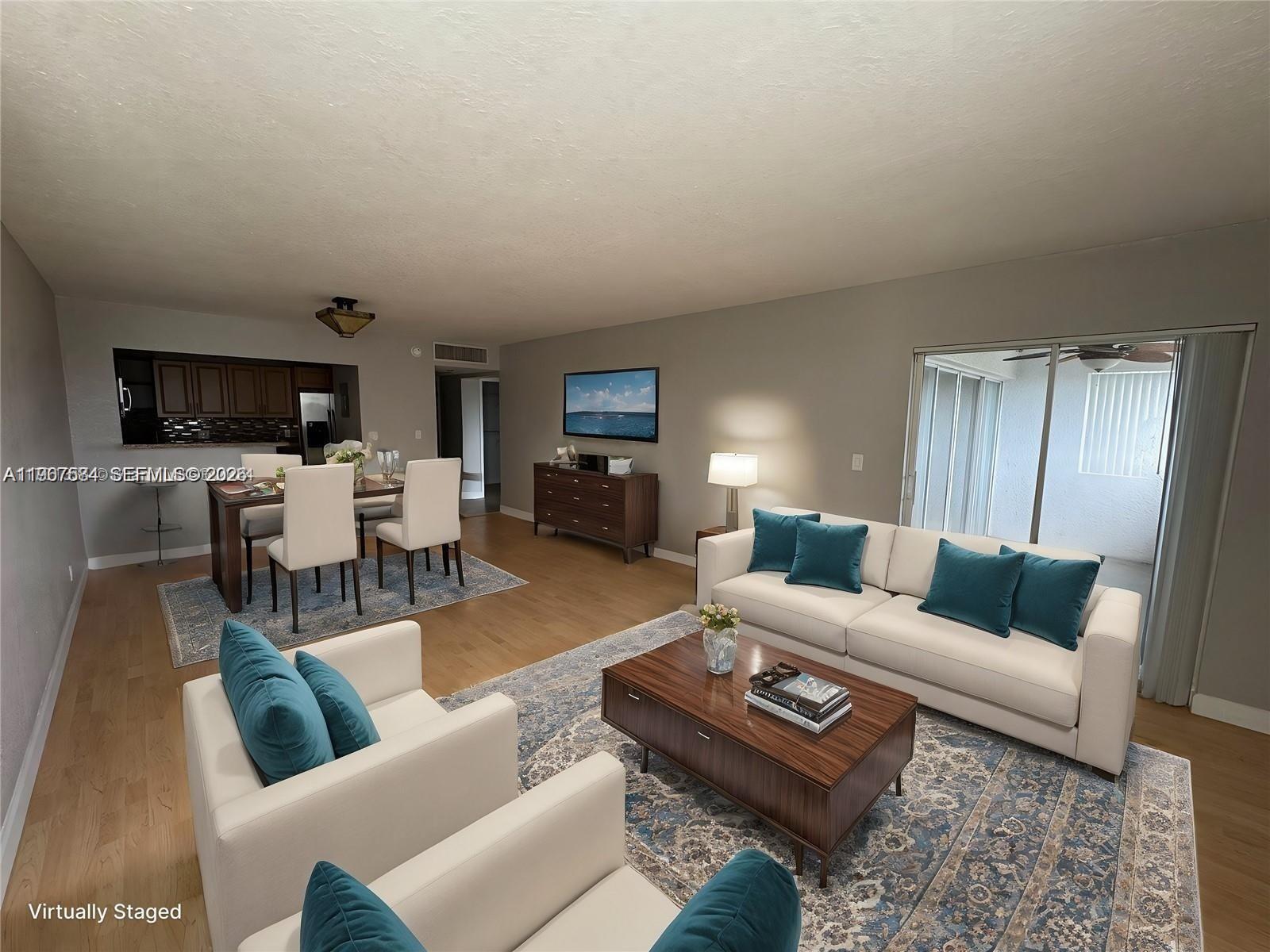 This living and dining area features wood flooring, a white sofa, and a kitchen — 3301 Spanish Moss Ter # 604, Lauderhill FL 33319, LAUDERHILL, FL