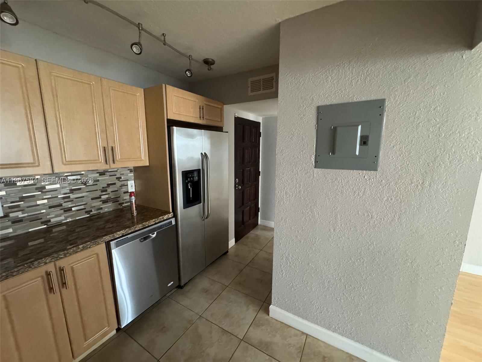 A kitchen features light wood cabinets, stainless steel appliances, and a gray electrical panel — 3301 Spanish Moss Ter # 604, Lauderhill FL 33319, LAUDERHILL, FL