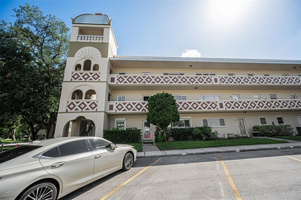 A multi-story apartment building with a decorative tower and patterned railings stands above a parking lot — 2384 TAHITIAN LANE UNIT 22, CLEARWATER, FL