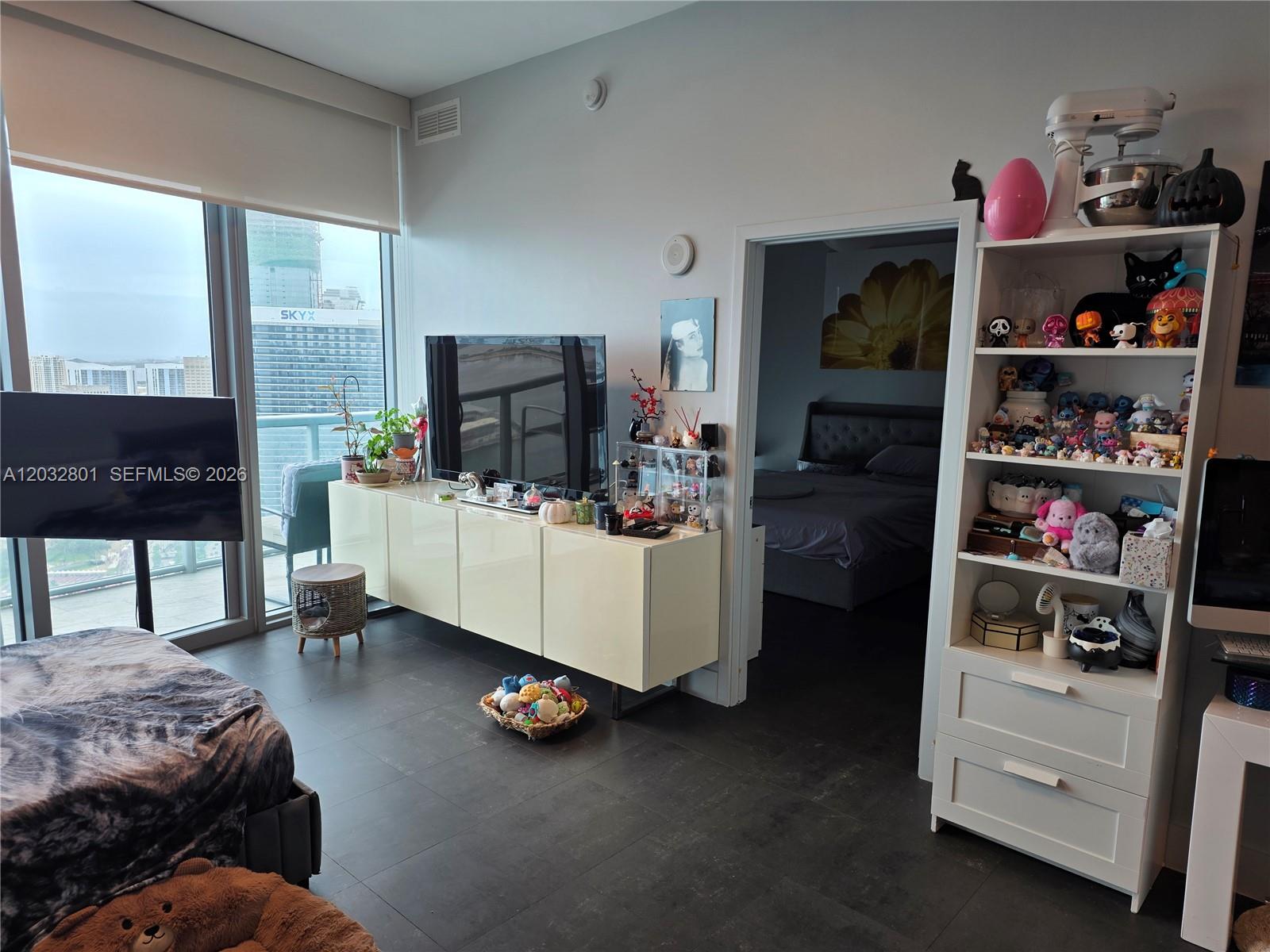 A living room features a television console, a display shelf, and a view of buildings — 888 Biscayne Blvd # 5107, Miami FL 33132, MIAMI, FL