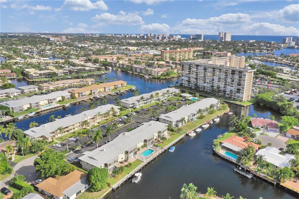 An aerial view shows multi-story residential buildings, swimming pools, and canals in a coastal neighborhood — 930 SE 9th Avenue # 11, Pompano Beach FL 33060, POMPANO BEACH, FL