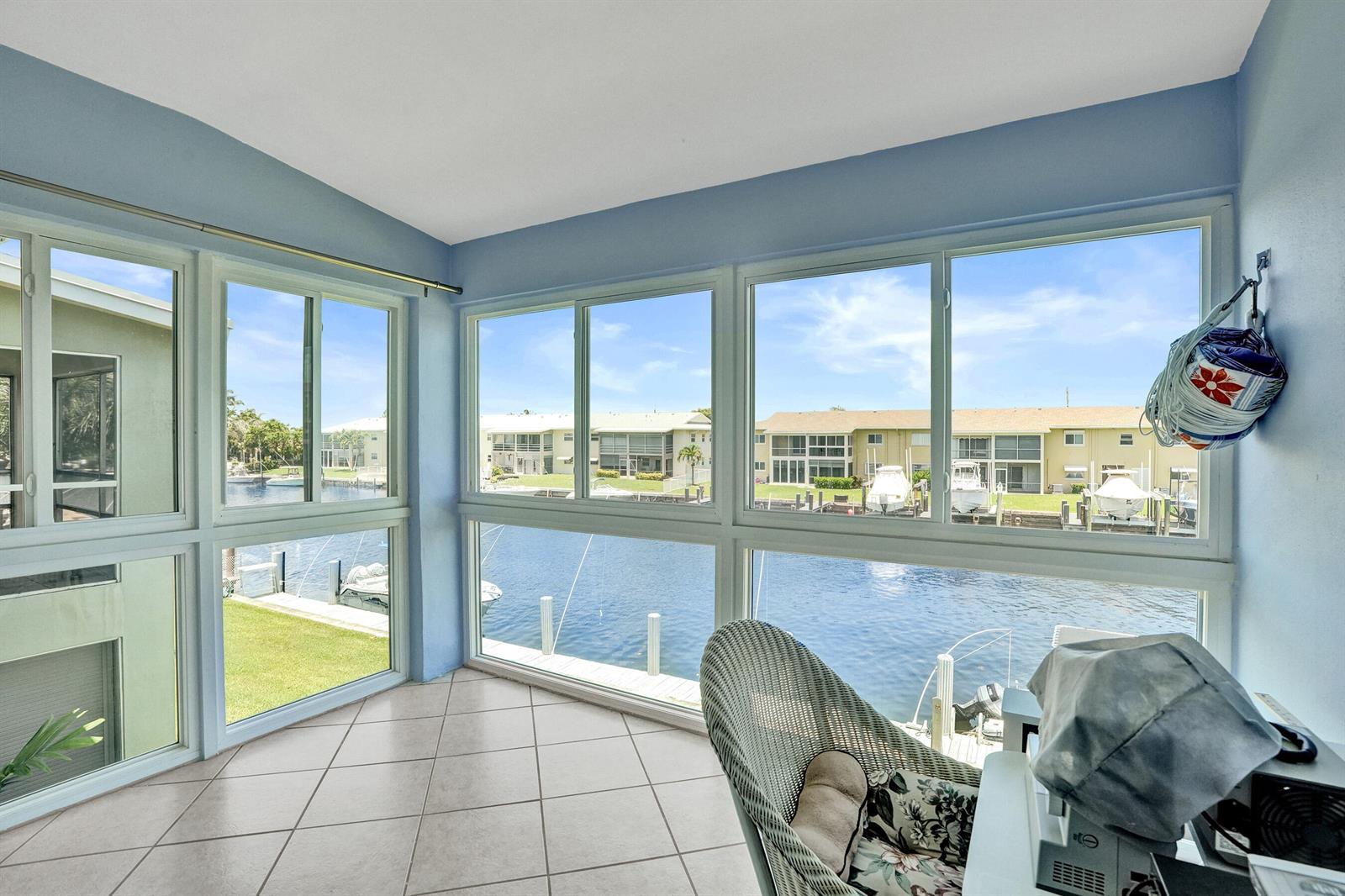 A sunroom with tile flooring and large windows overlooking a canal with docked boats — 930 SE 9th Avenue # 11, Pompano Beach FL 33060, POMPANO BEACH, FL