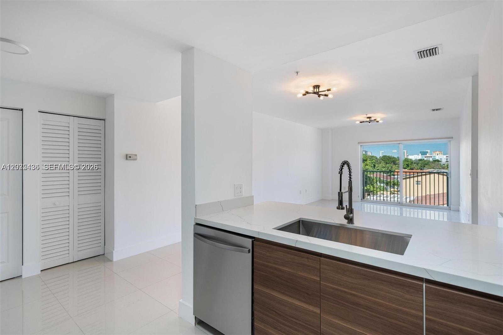 A modern kitchen features a stainless steel sink, wood-grain cabinets, and a white countertop — 2280 SW 32nd Ave # 201, Miami FL 33145, MIAMI, FL