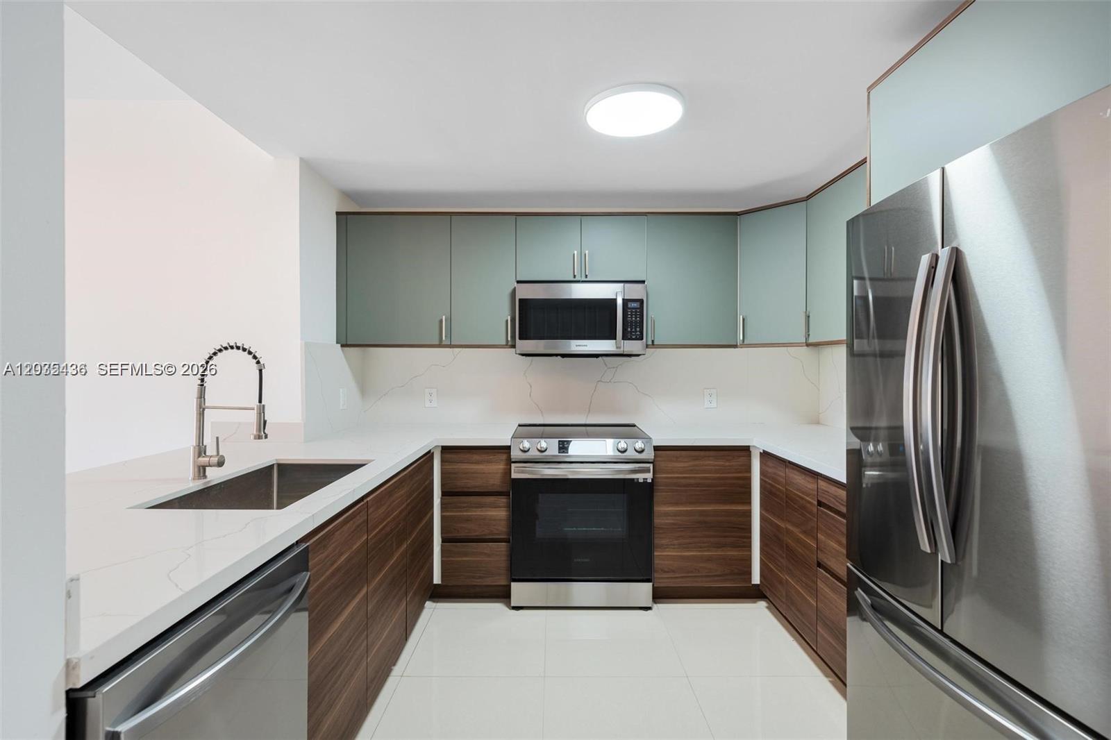 A modern kitchen features wood-grain lower cabinets, light green upper cabinets, and white countertops — 2280 SW 32nd Ave # 201, Miami FL 33145, MIAMI, FL