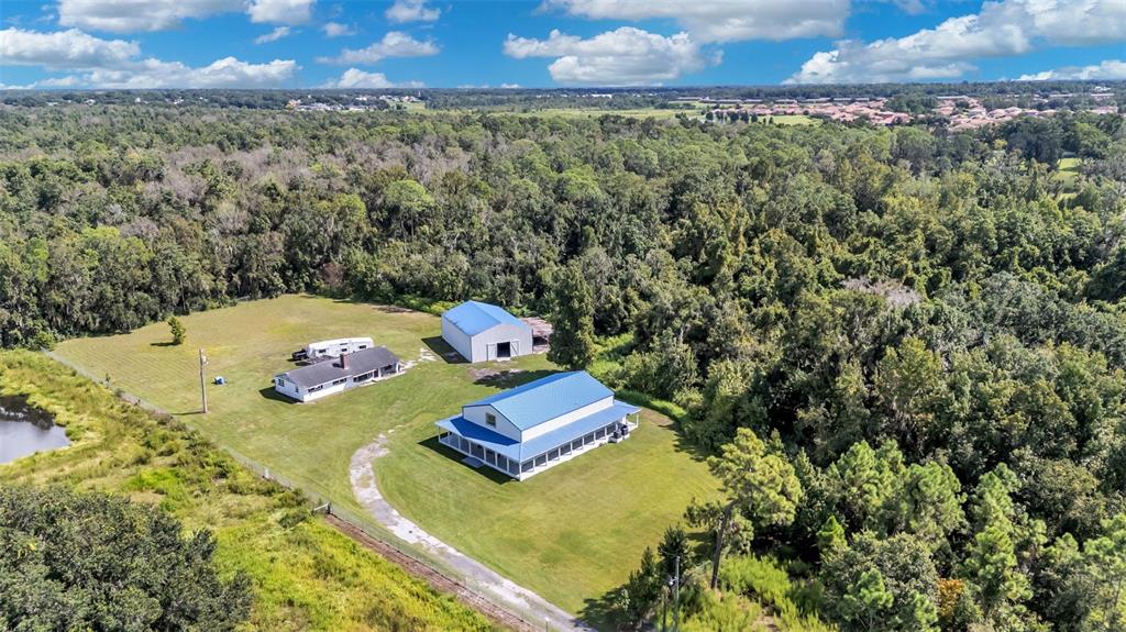 An aerial view shows a house, a large barn, and a smaller outbuilding on acreage — 4141 KATHLEEN ROAD, LAKELAND, FL