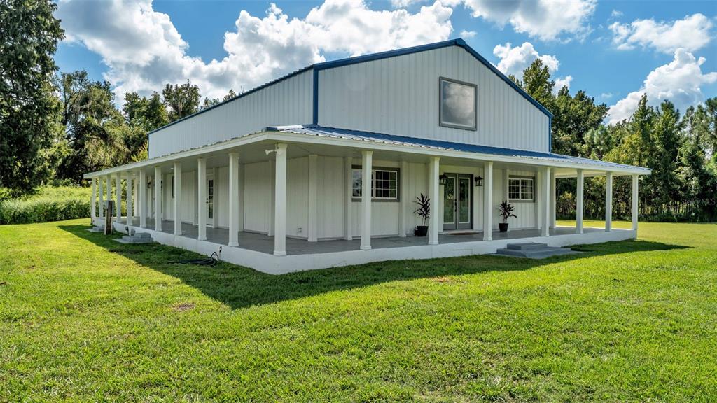 A white metal building with a wraparound porch stands in a grassy field — 4141 KATHLEEN ROAD, LAKELAND, FL
