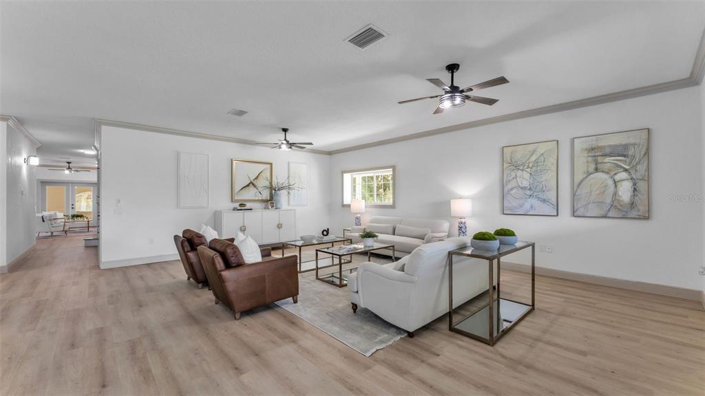 A bright living room features light wood flooring, white walls, and a neutral furniture arrangement — 4141 KATHLEEN ROAD, LAKELAND, FL