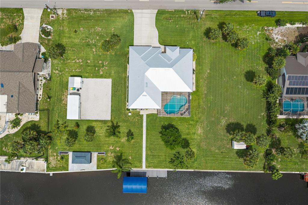 An aerial view shows a house with a pool, boat dock, and large grassy yard — 1052 EPPINGER DRIVE, PORT CHARLOTTE, FL