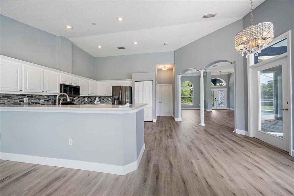 A kitchen with white cabinets and a breakfast bar opens into a living area — 1052 EPPINGER DRIVE, PORT CHARLOTTE, FL