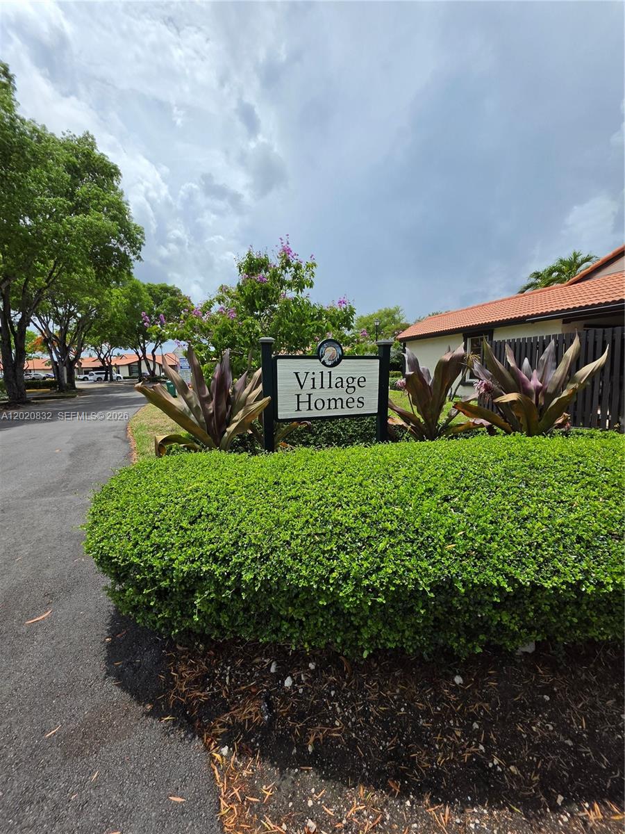 A sign for Village Homes stands behind a manicured hedge in a residential area — 15240 SW 45th Ter # 54F, Miami FL 33185, MIAMI, FL