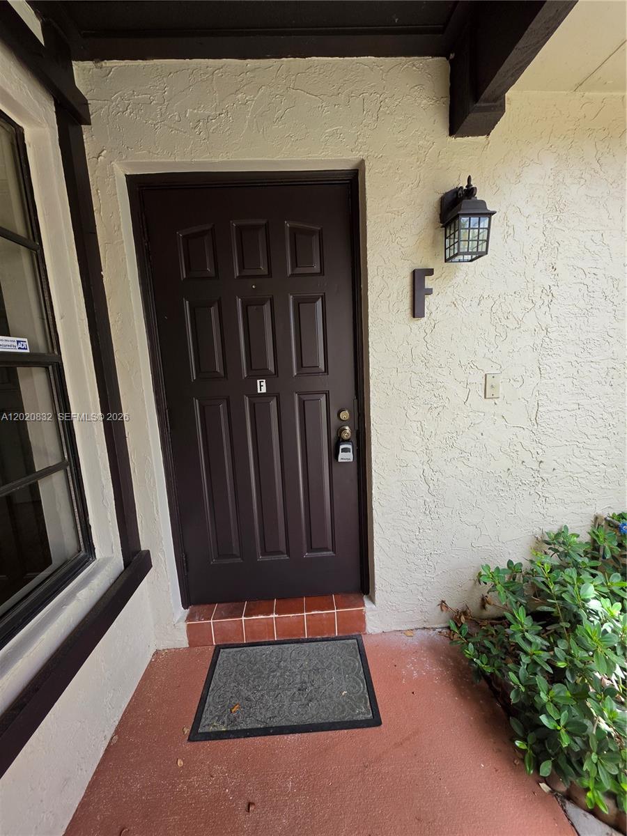 A dark brown front door with an "F" label is set in a stucco exterior wall — 15240 SW 45th Ter # 54F, Miami FL 33185, MIAMI, FL