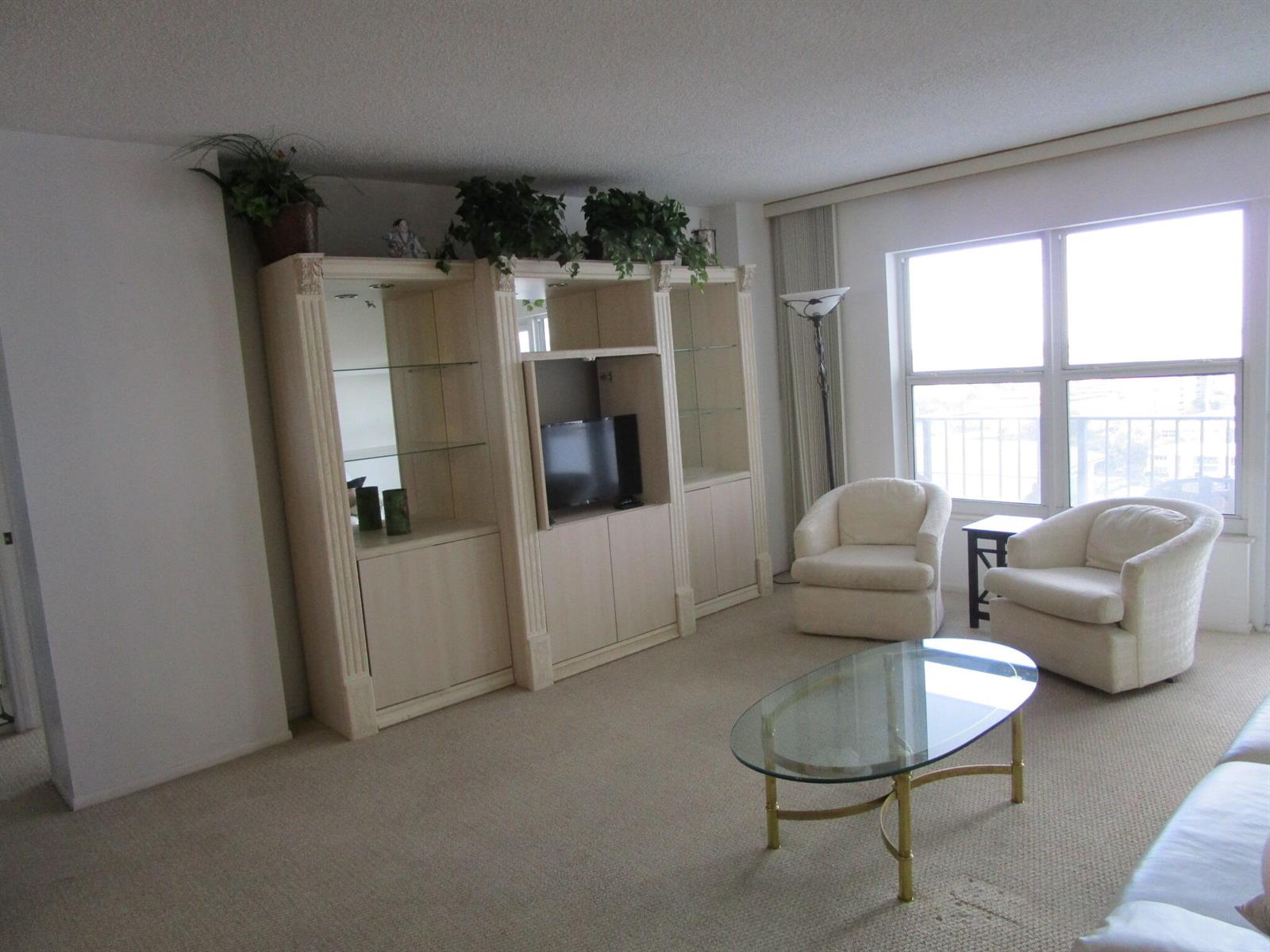A living room features a large light-wood wall unit, two cream armchairs, and a glass-topped table — 405 N Ocean Boulevard # 1225, Pompano Beach FL 33062, POMPANO BEACH, FL
