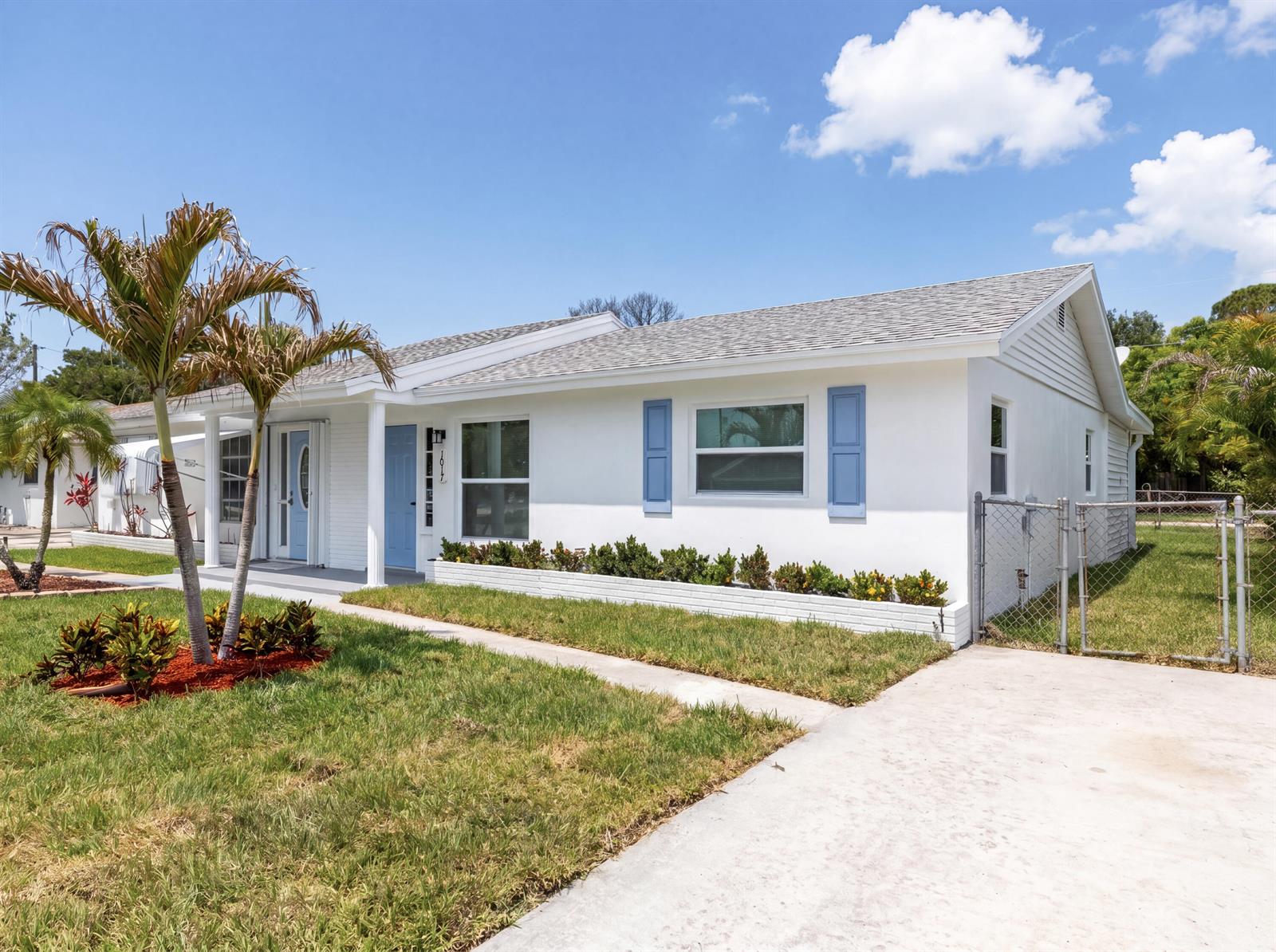 A white single-story house with blue shutters, a front porch, and a concrete driveway — 1017 Riverwood Lane, Jupiter FL 33458, JUPITER, FL
