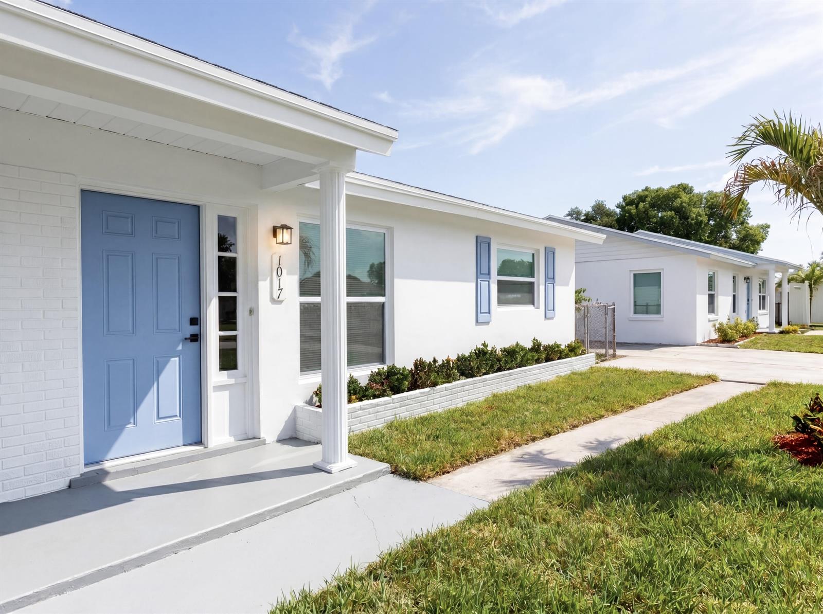 A white house exterior features a light blue front door, blue shutters, and a porch — 1017 Riverwood Lane, Jupiter FL 33458, JUPITER, FL