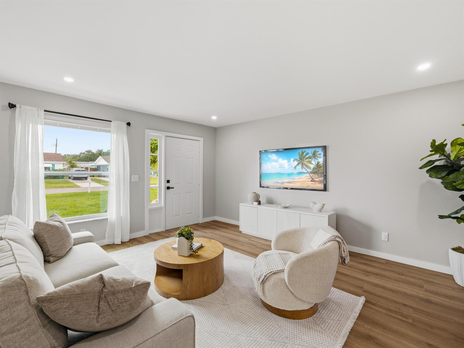 A living room features light gray walls, wood-look flooring, a white media console, and furniture — 1017 Riverwood Lane, Jupiter FL 33458, JUPITER, FL
