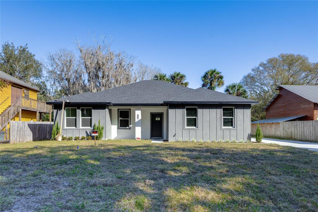 A single-story gray house with a dark roof stands on a grassy lot — 127 HIBISCUS LANE, DELTONA, FL