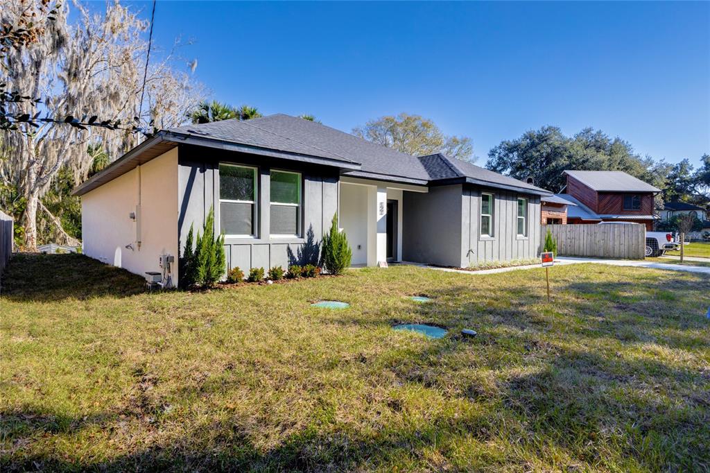 A single-story house with gray vertical siding and a dark roof sits on a lawn — 127 HIBISCUS LANE, DELTONA, FL