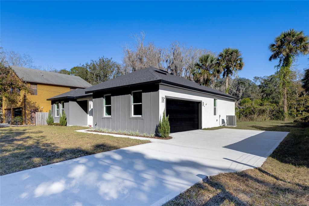 A modern single-story house with a two-tone exterior, dark garage door, and concrete driveway — 127 HIBISCUS LANE, DELTONA, FL
