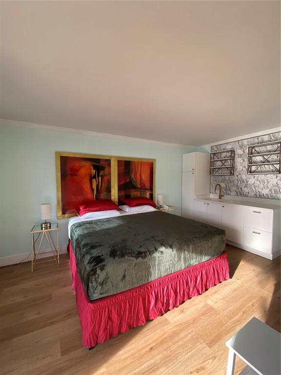 A bedroom features a bed with a pink skirt, abstract wall art, and a kitchenette — 7150 N TAMIAMI TRAIL UNIT S521, SARASOTA, FL