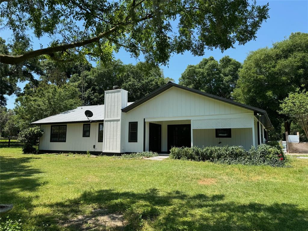 A white house with a metal roof and a covered porch sits on a lawn — 7111 SW 80TH AVENUE, OCALA, FL