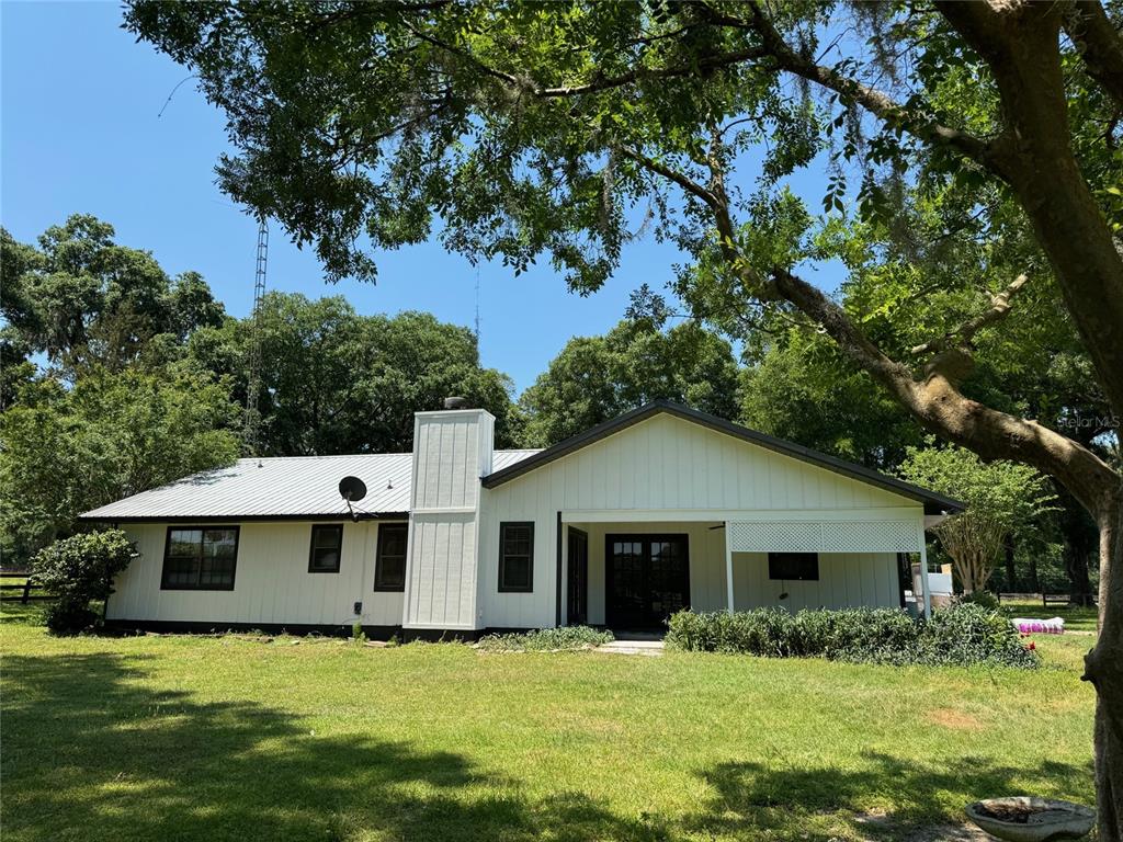 A white, single-story house with a metal roof and a large chimney sits on grass — 7111 SW 80TH AVENUE, OCALA, FL