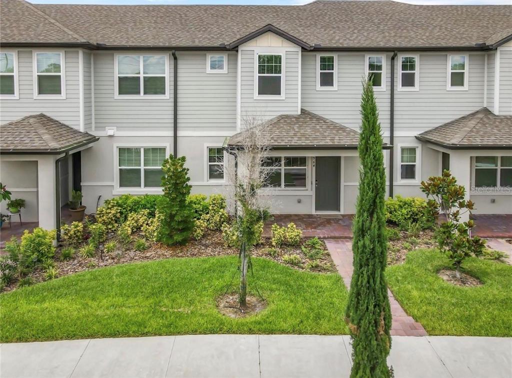 A two-story townhouse exterior with light gray siding, a brick walkway, and landscaped front yard — 964 LEGACY WINDS WAY, CASSELBERRY, FL