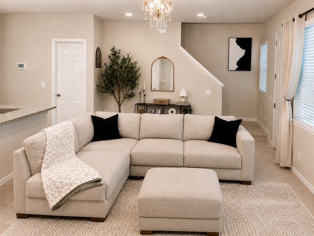 A living room features a beige sectional sofa, a matching ottoman, and a decorative mirror — 964 LEGACY WINDS WAY, CASSELBERRY, FL