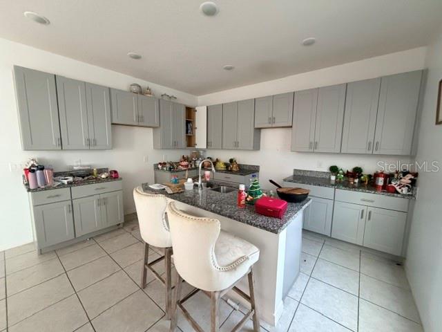 A kitchen features gray cabinets, granite countertops, a central island, and light-colored tile flooring — 270 TARPON BAY BOULEVARD, HAINES CITY, FL