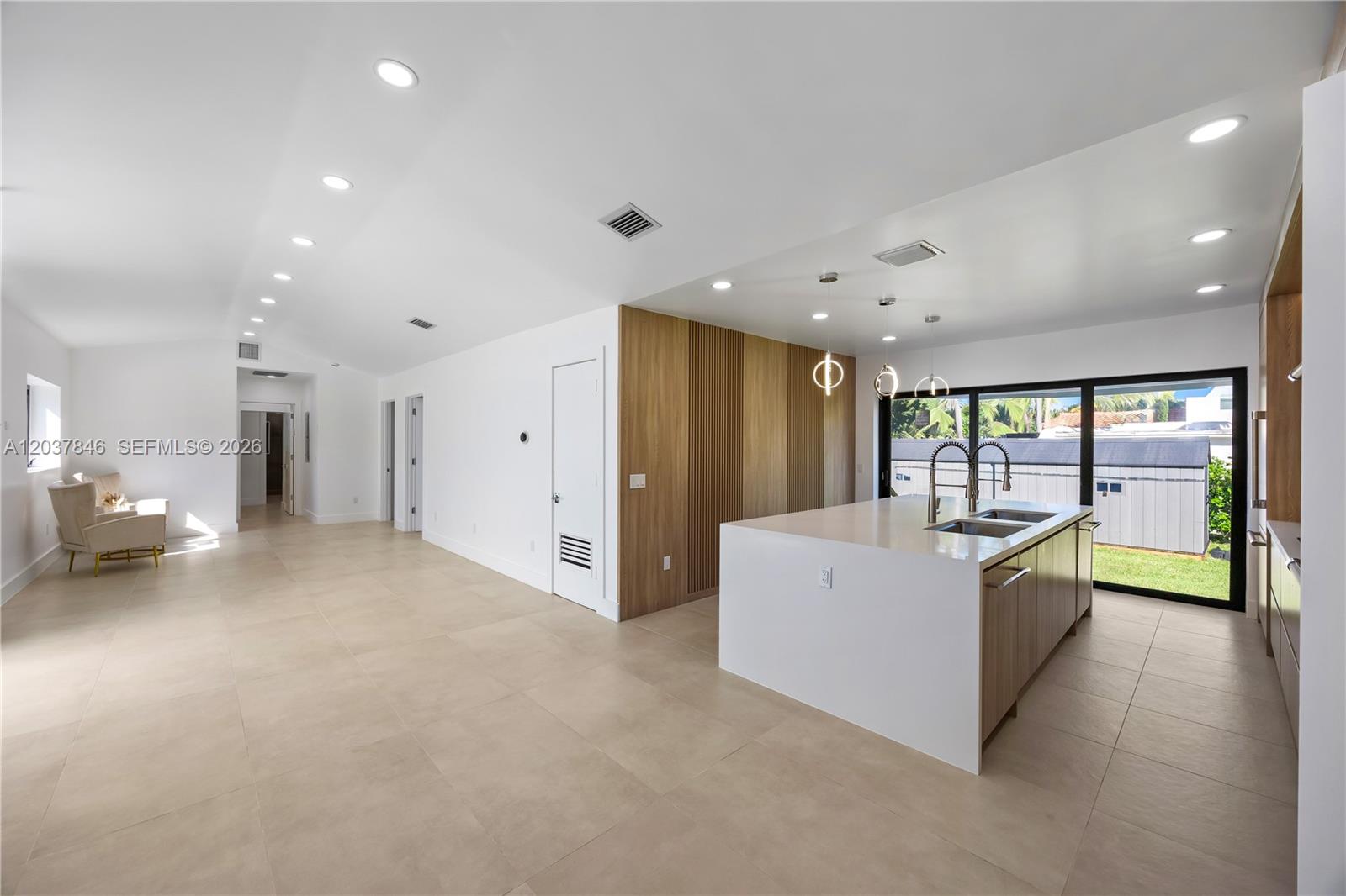 A modern kitchen features a large white island, wood-slat wall accents, and light tile flooring — 1141 Hollywood Blvd, Hollywood FL 33019, HOLLYWOOD, FL