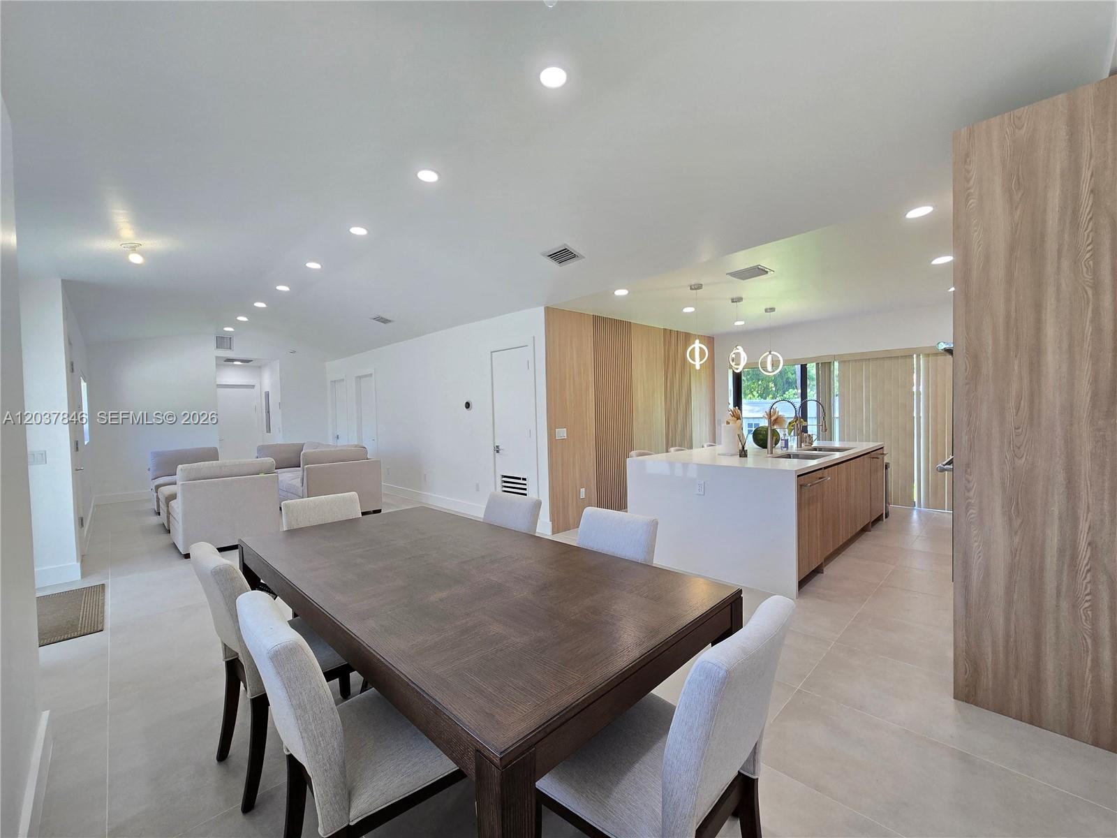 An open-concept living area features a dining table, a kitchen island, and light-colored tile flooring — 1141 Hollywood Blvd, Hollywood FL 33019, HOLLYWOOD, FL