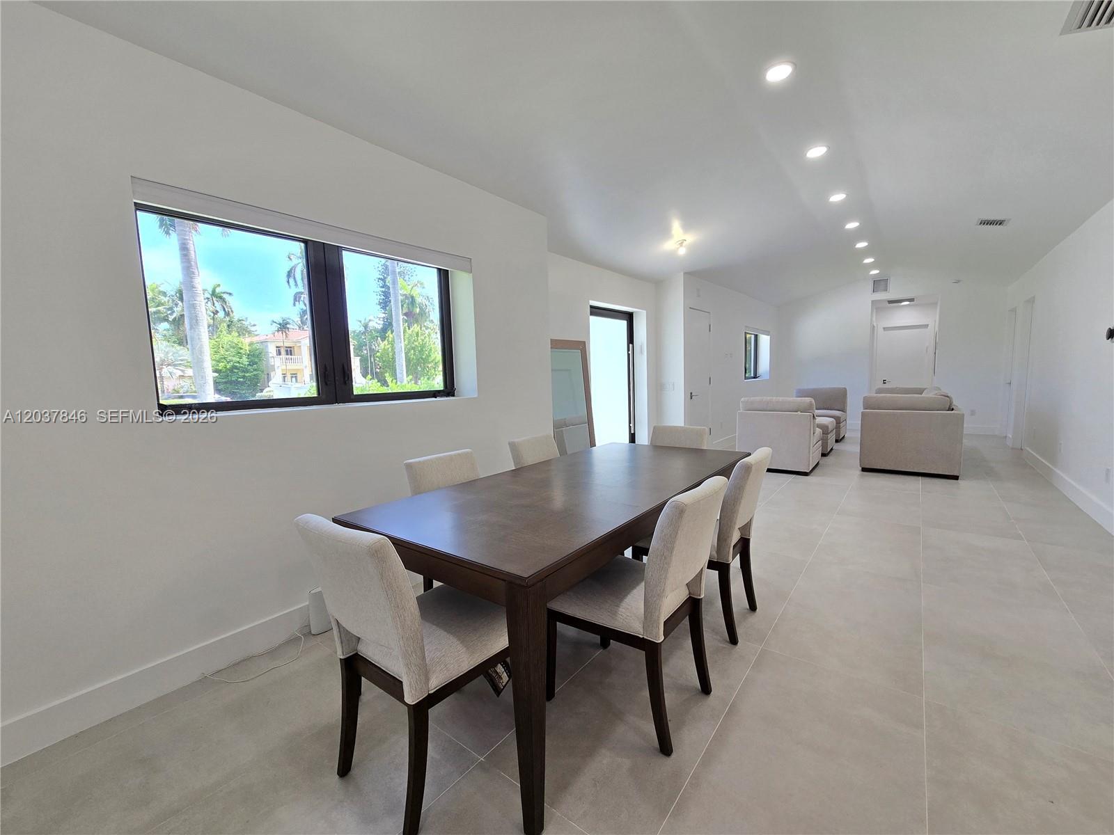 A dining area with a dark wood table and chairs sits before a large window — 1141 Hollywood Blvd, Hollywood FL 33019, HOLLYWOOD, FL