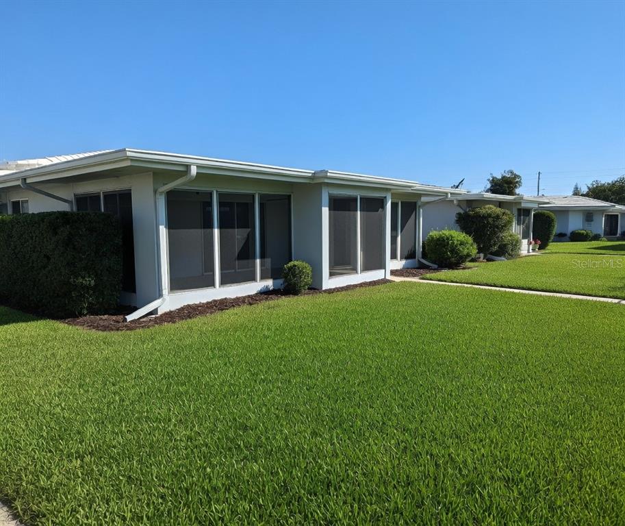 A low-slung, light-colored house with a screened-in porch and a large, well-maintained green lawn — 3280 SOUTHFIELD LANE UNIT 804, SARASOTA, FL
