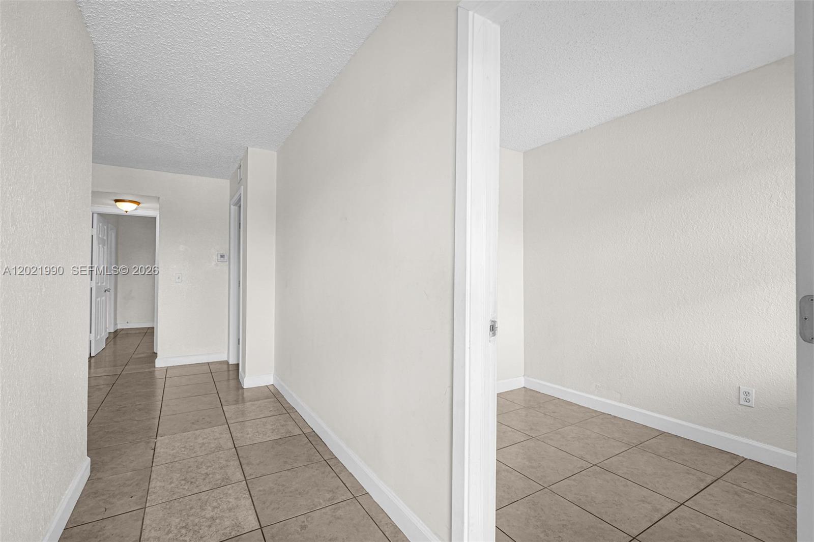 A hallway with light-colored walls and tile flooring leads to an open doorway — 400 NW 65th Ave # 222, Margate FL 33063, MARGATE, FL