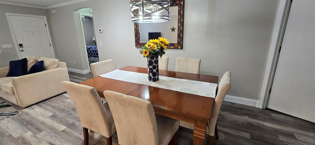 A dining room features a wooden table with six chairs, a centerpiece, and a chandelier — 712 ARTESIA AVENUE, THE VILLAGES, FL