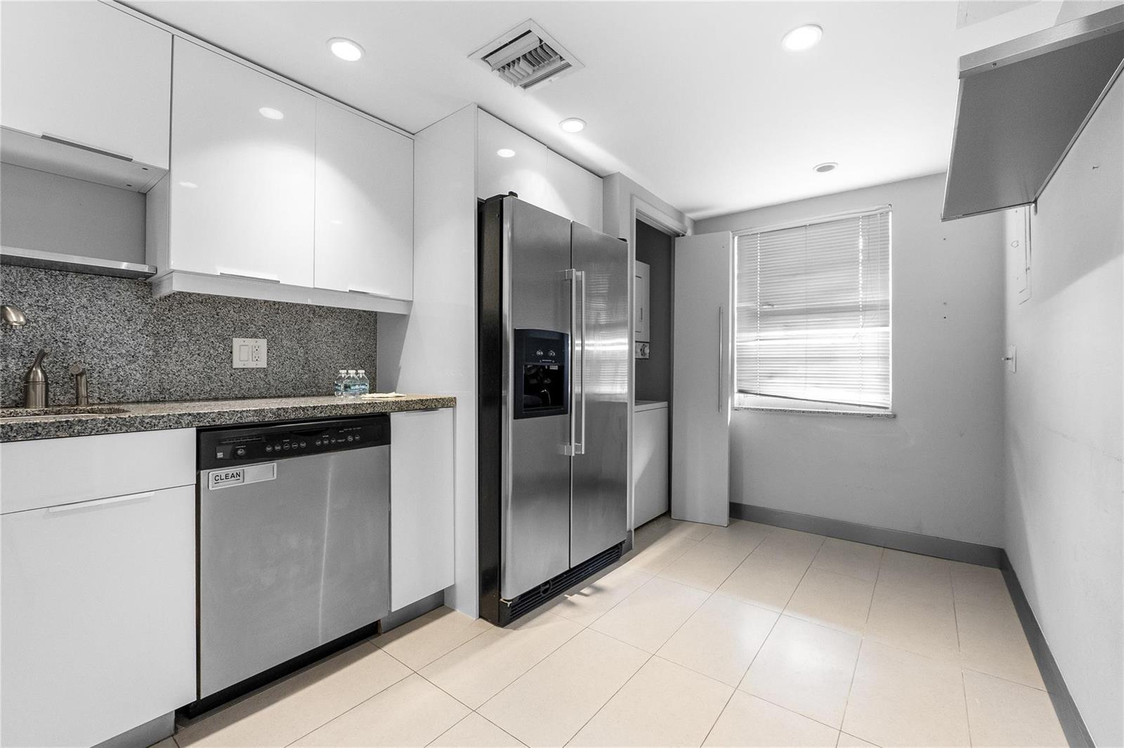 A kitchen features white cabinets, stainless steel appliances, granite countertops, and a laundry closet — 535 Oaks Drive # 508, Pompano Beach FL 33069, POMPANO BEACH, FL