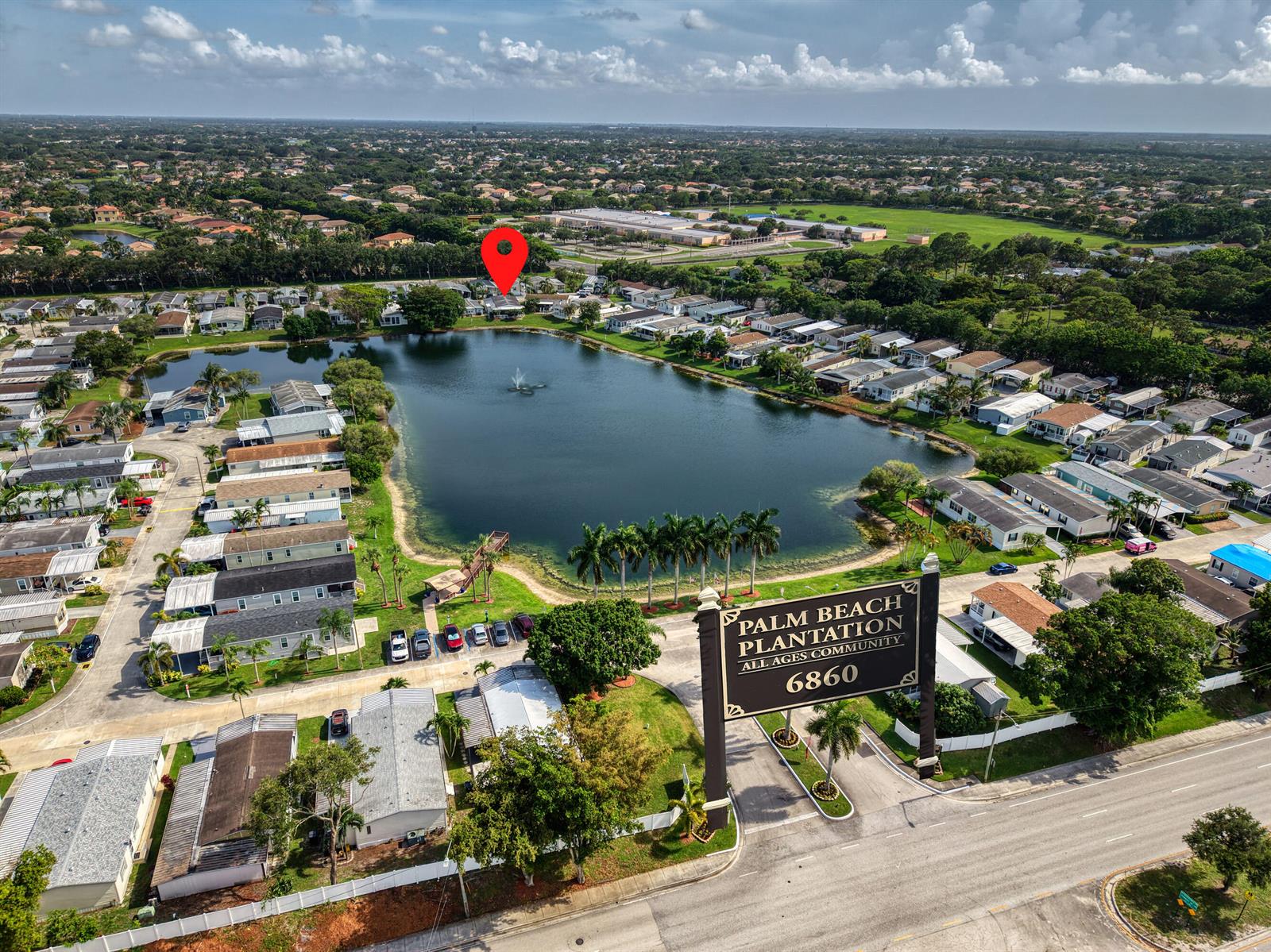 An aerial view shows a residential community with a central lake and a large sign — 139 Plantation Boulevard, FL 33467, FL