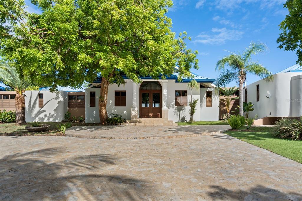 A white house with a stone driveway, a large tree, and a blue metal roof — 37 BARRIO FRAILES, CULEBRA, PR